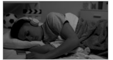 Jeune allongé dans son lit avec un casque audio, pour rappeler d’éviter le casque audio avant de dormir.